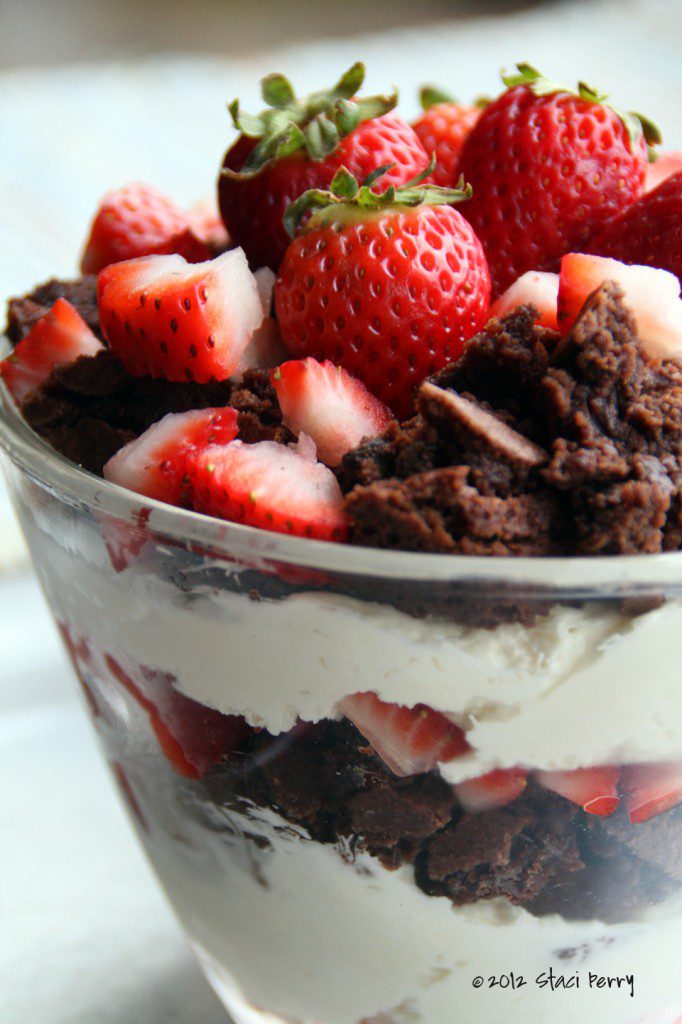 bowl with layers of white chocolate and cream cheese cream, brownies, and sliced strawberries 