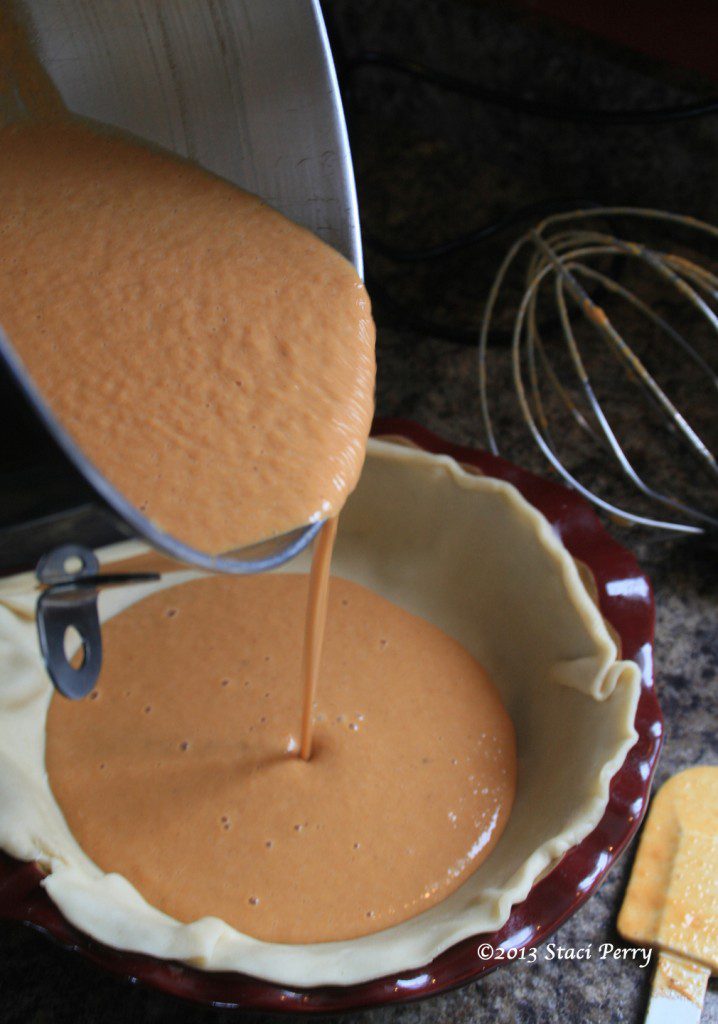 pouring pumpkin pie filling into pie shell