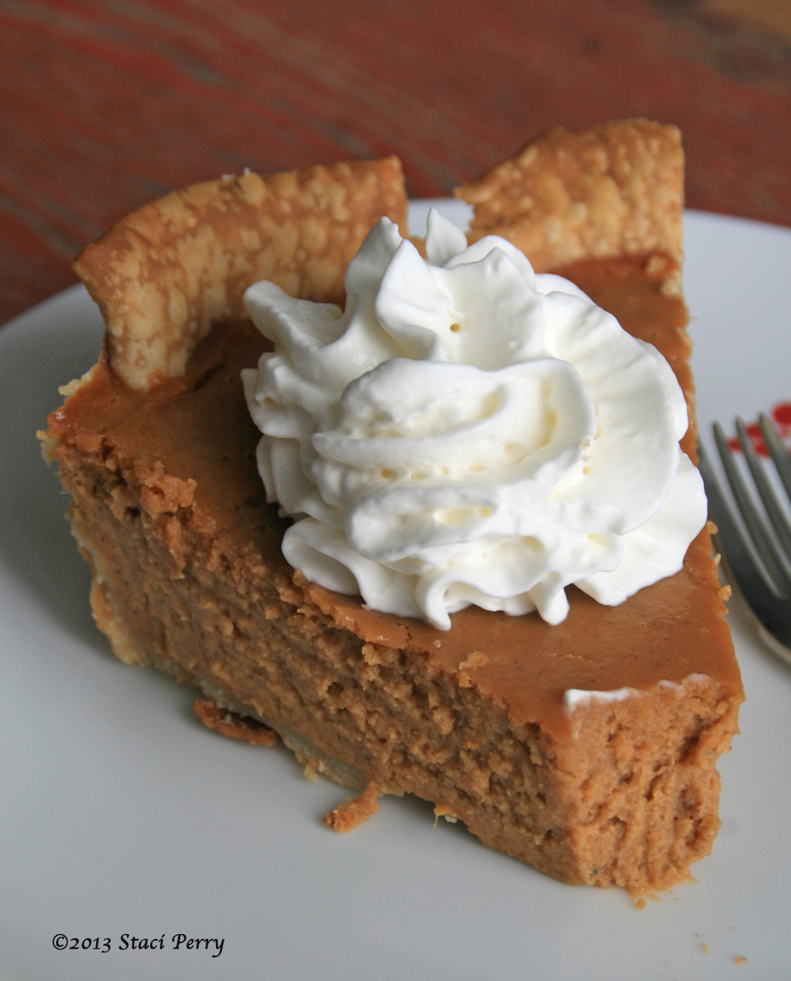 plate with slice of pumpkin pie with a dollop of whipped cream