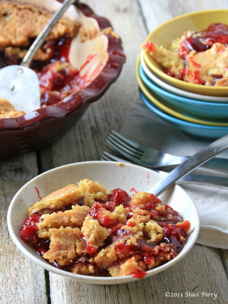 bowl of cherry crunch and a pie plate with cherry crunch in the background 