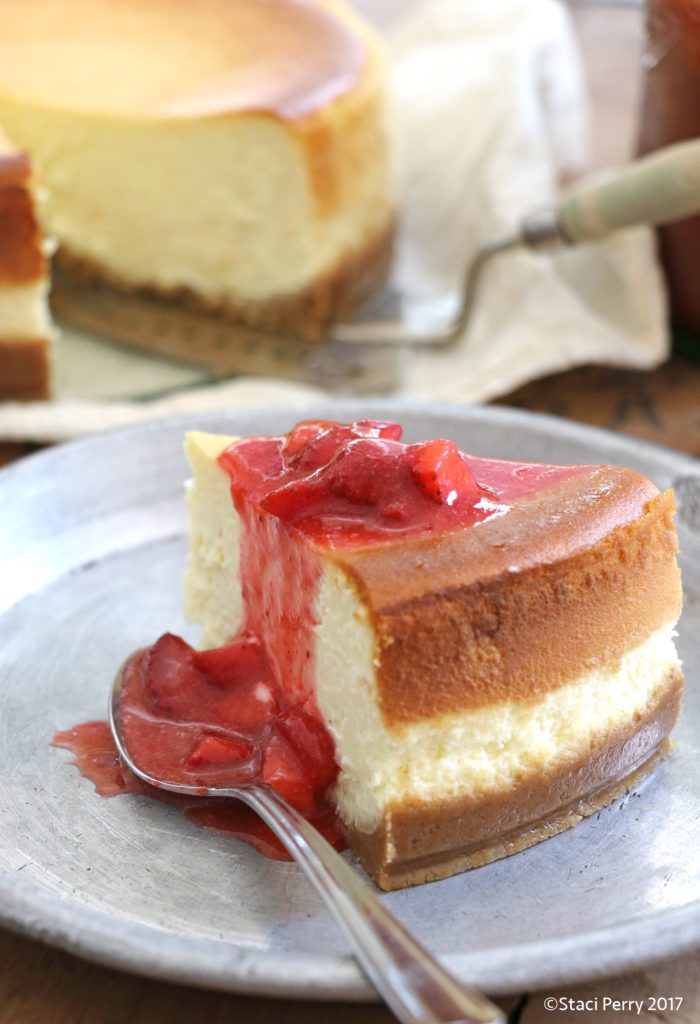 slice of vanilla cheesecake on plate with strawberry sauce