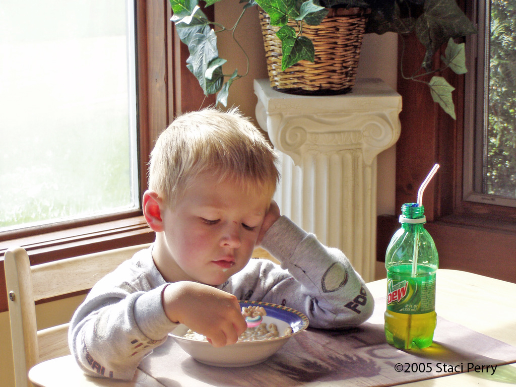 child eating Lucky Charms cereal with Mountain Dew bottle with straw