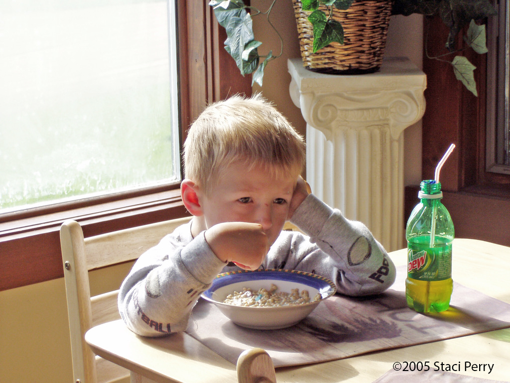 child eating Lucky Charms cereal with Mountain Dew bottle with straw