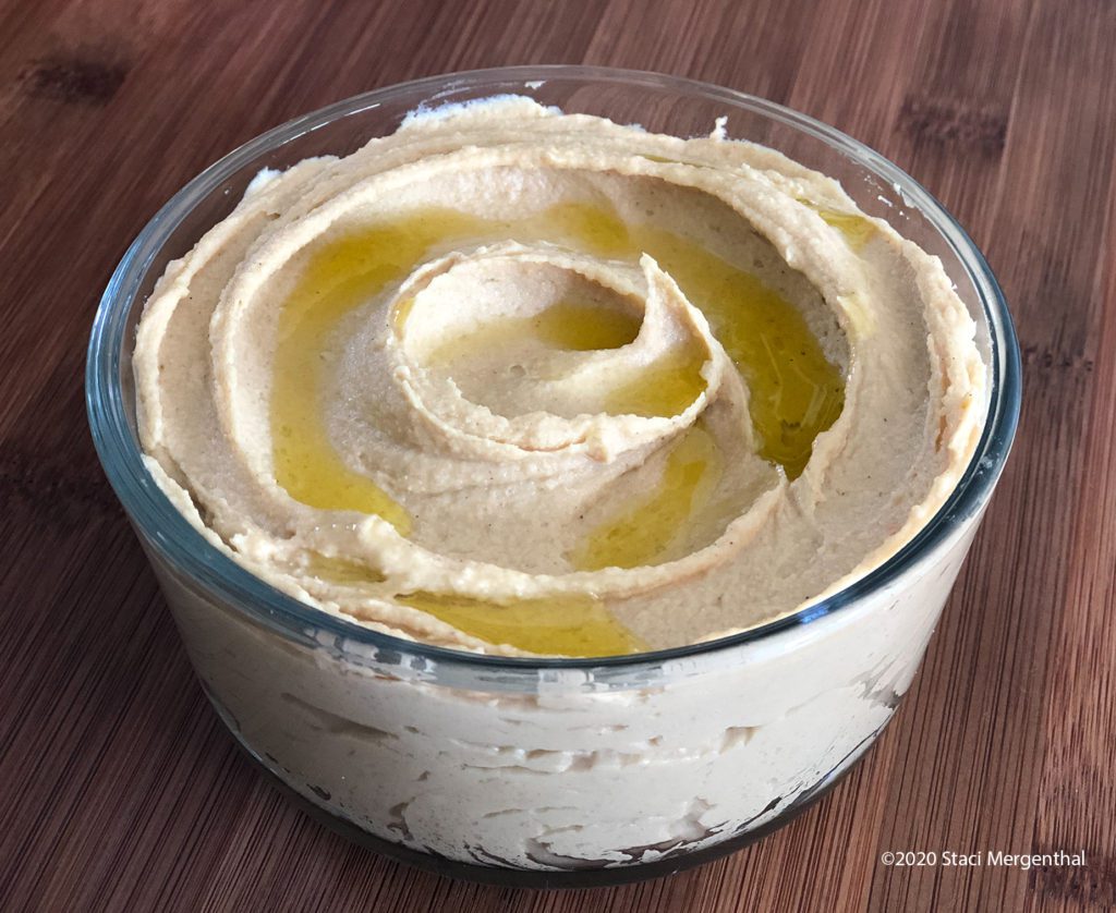 bowl of creamy smooth garlic hummus drizzled with olive oil 