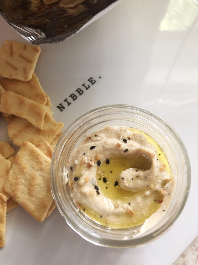 4 ounce glass jar of hummus with a side of crackers