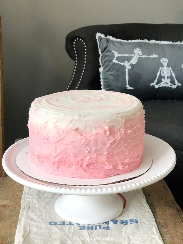 3-layer cake with pink and white frosting on a white cake stand