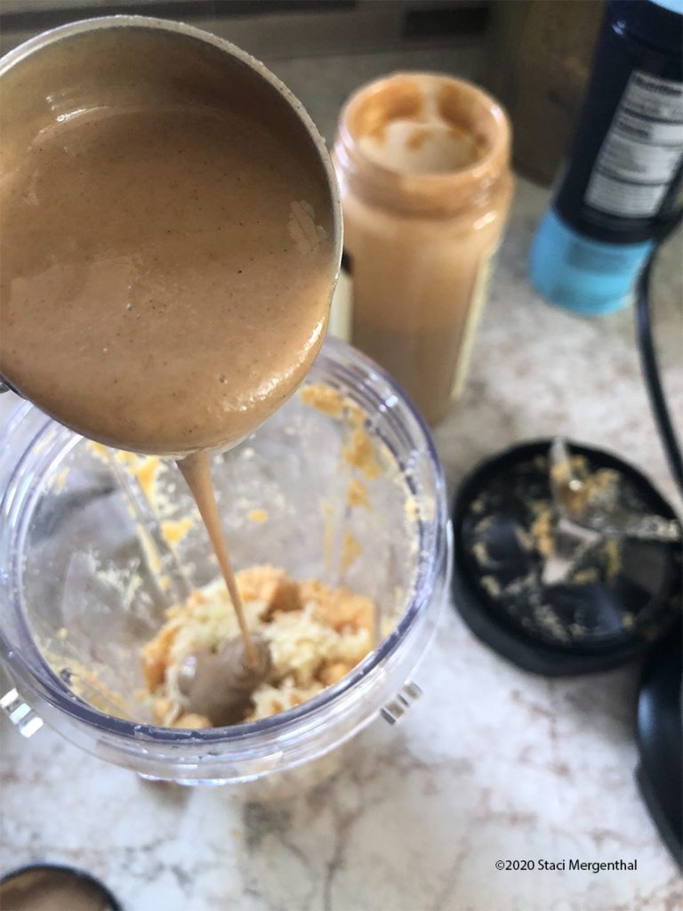 pouring tahini into blended chickpeas 