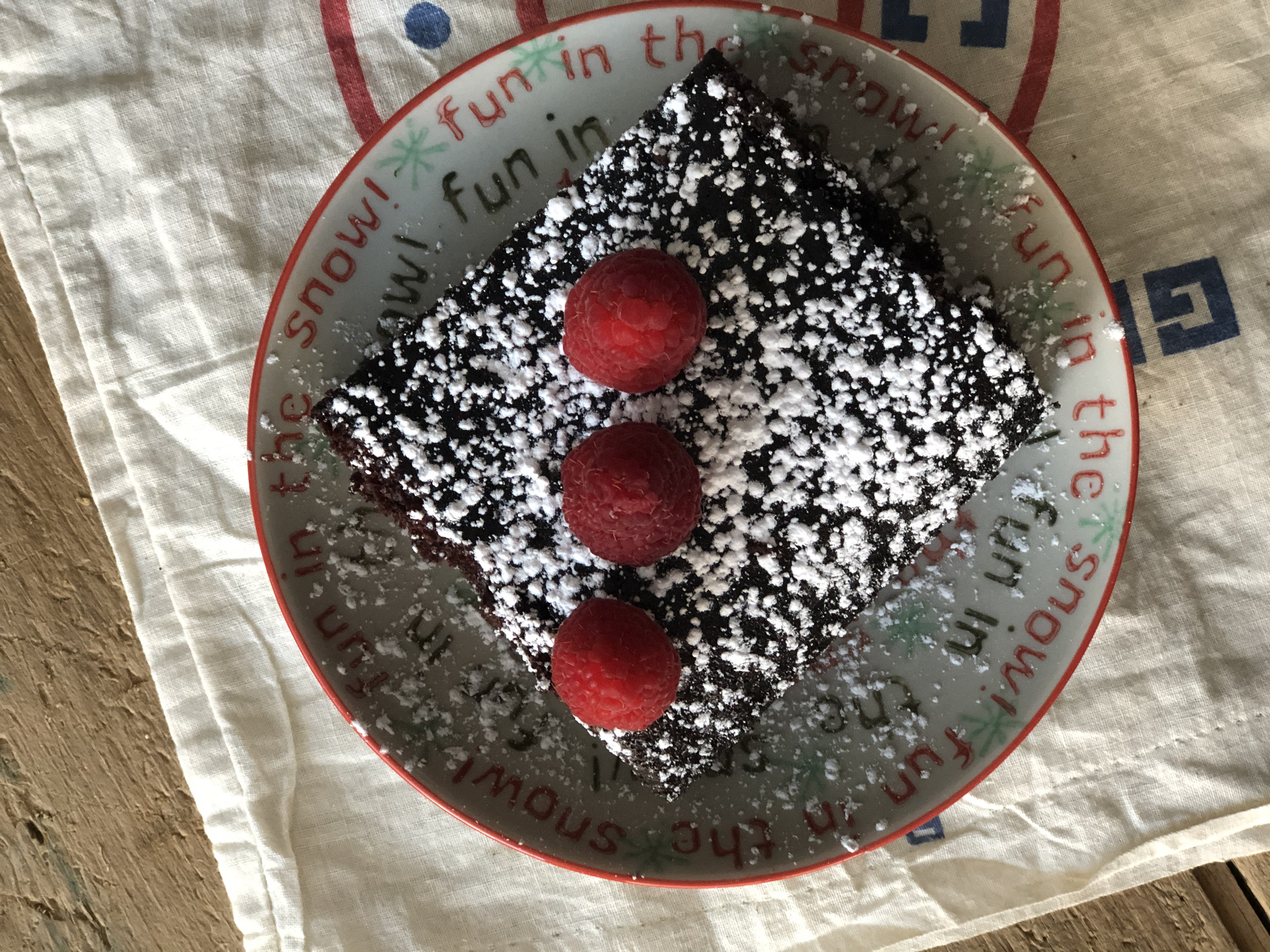 chocolate cake on a plate with raspberries on top