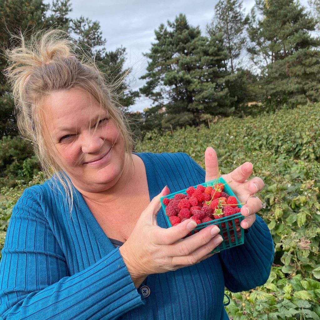 lady holding raspberries at raspberry patch
