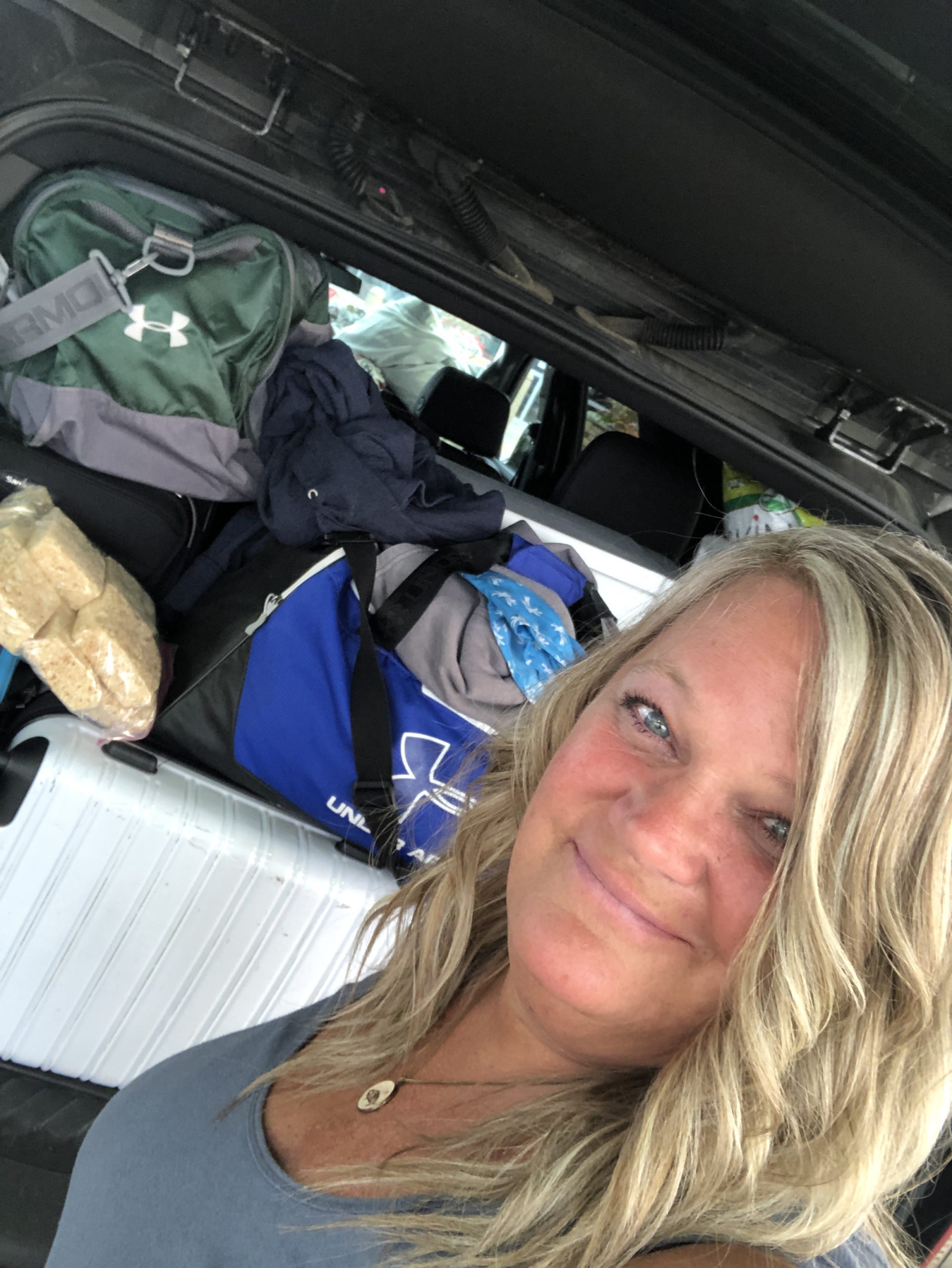 lady in front of Suburban with the back open filled with luggage