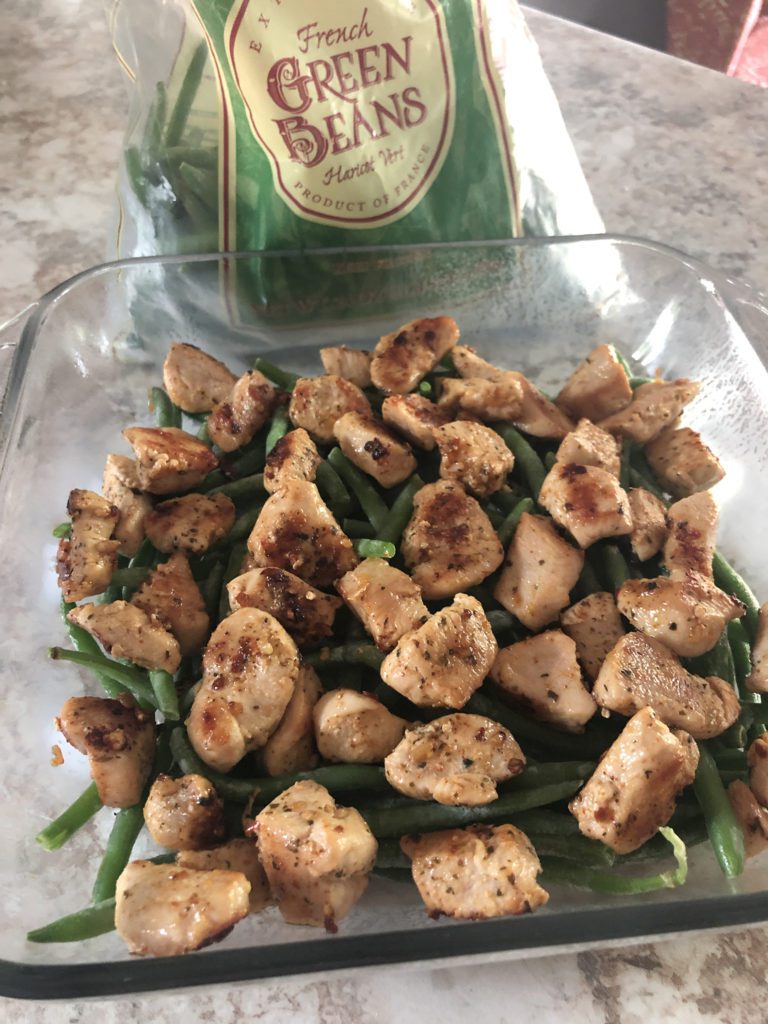 cooked chicken cube layered on top of green bean layer in pan