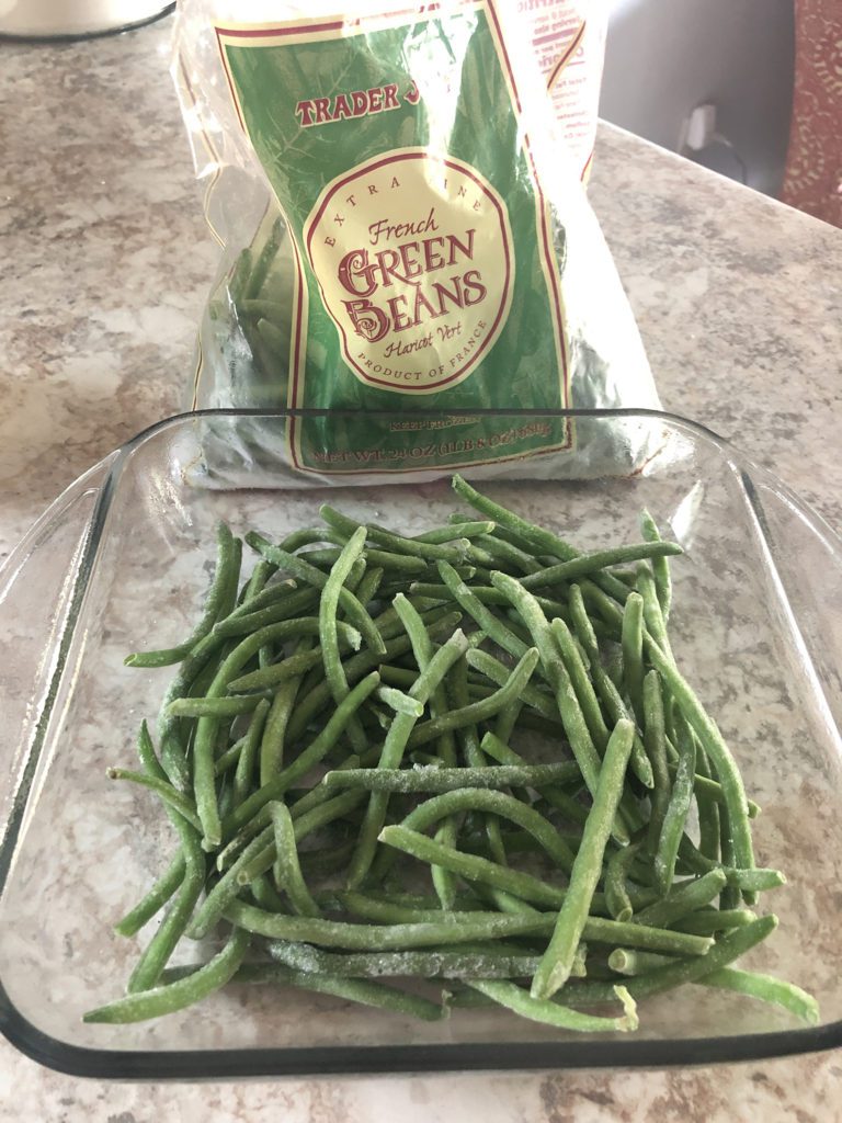 8x8 glass pan with frozen green beans layered on bottom