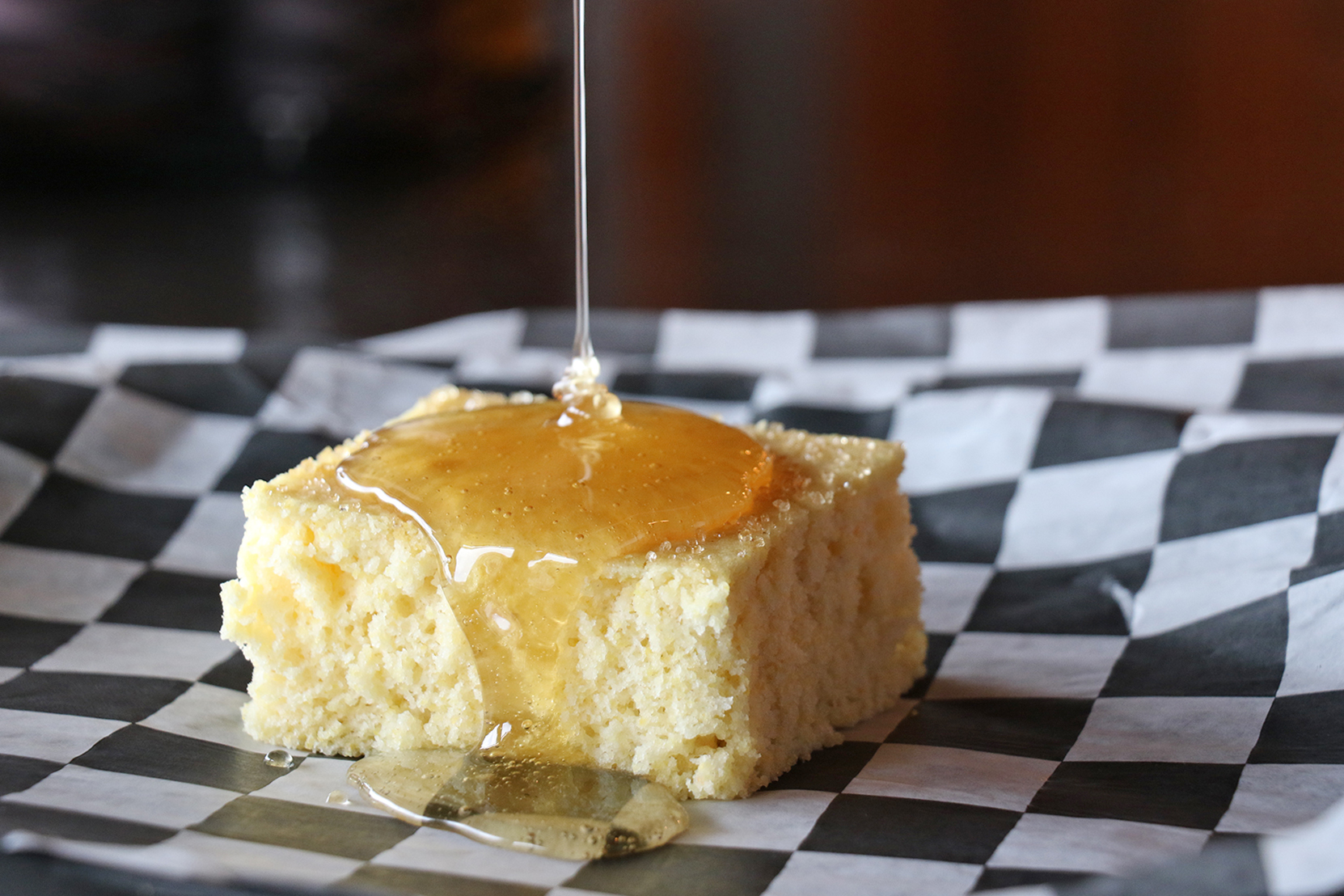 piece of cornbread with honey being drizzled on top