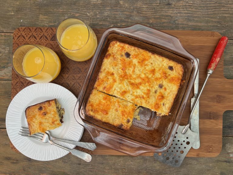 hash brown breakfast casserole in a pan with 2 glasses of orange juice