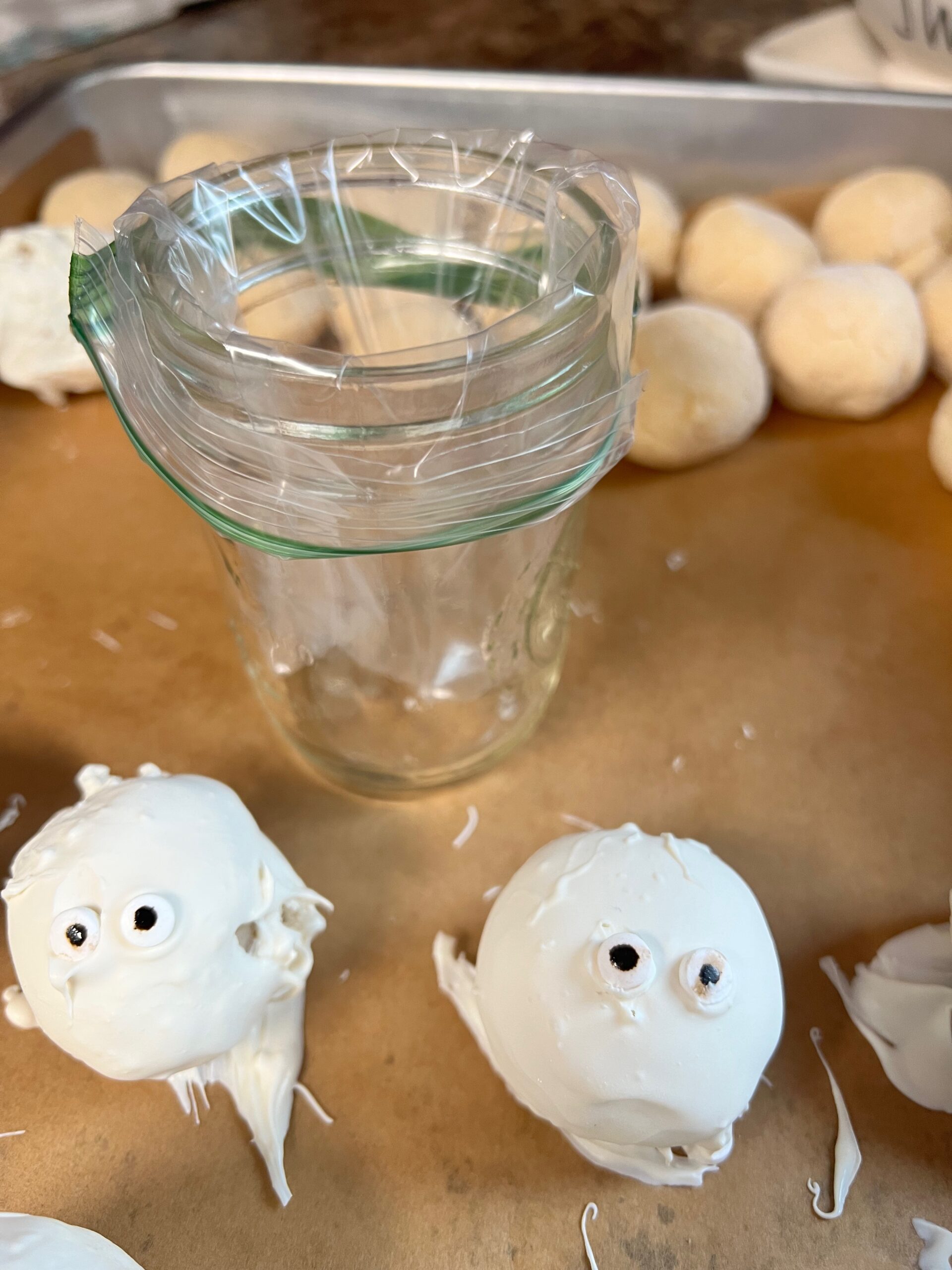 mummy cake balls with first layer of almond bark and eyeballs and jar with small zipper bag