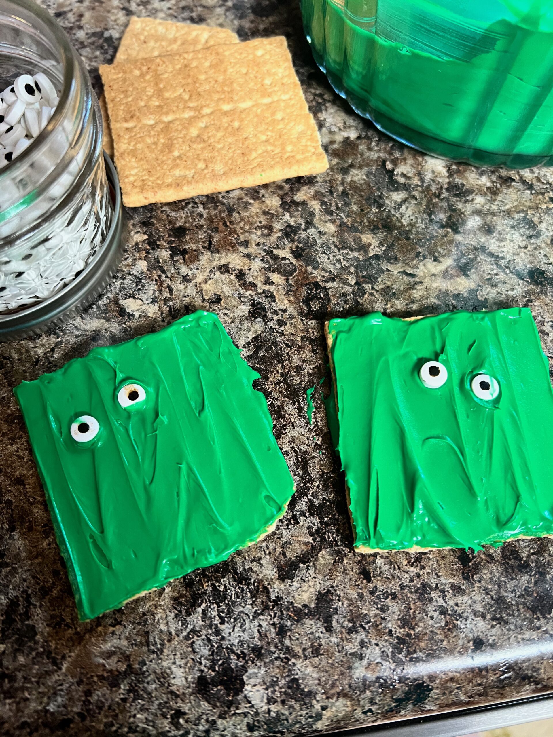 graham crackers frosted with green frosting and eyeballs