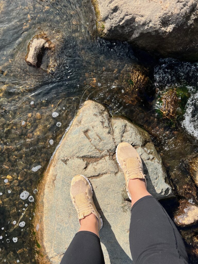 standing with tennis shoes on a rock in the river