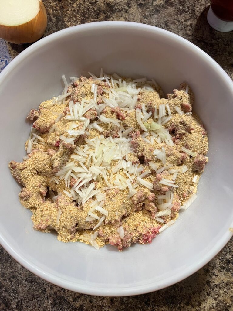 diced onion added to meatloaf mixture in a bowl
