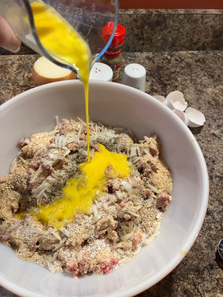 2 beaten eggs added to meatloaf mixture in a bowl