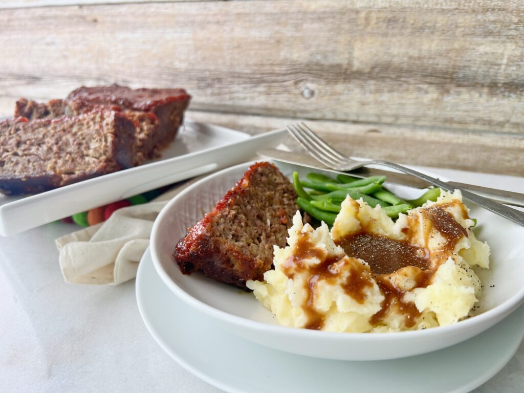 slice of meatloaf with mashed potatoes and green beans