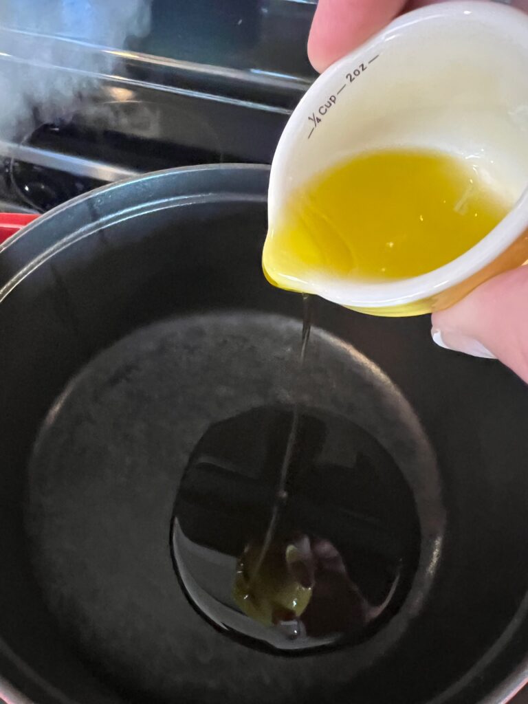 adding olive oil to spicy vodka pasta with chicken recipe