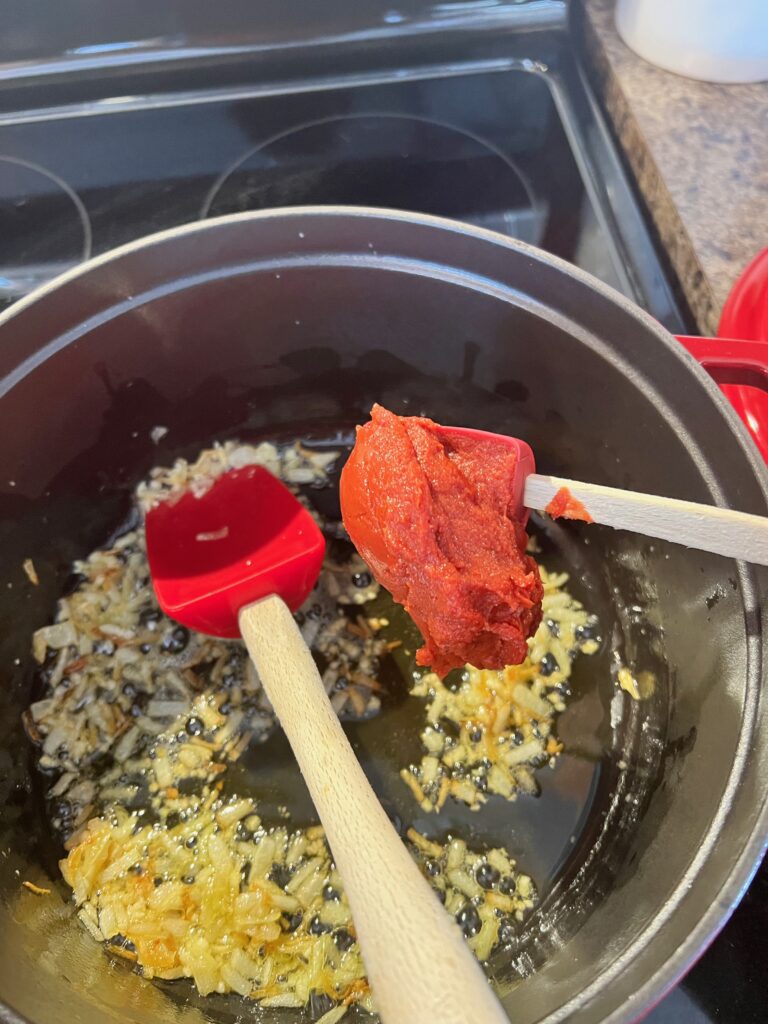 adding tomato paste to pot