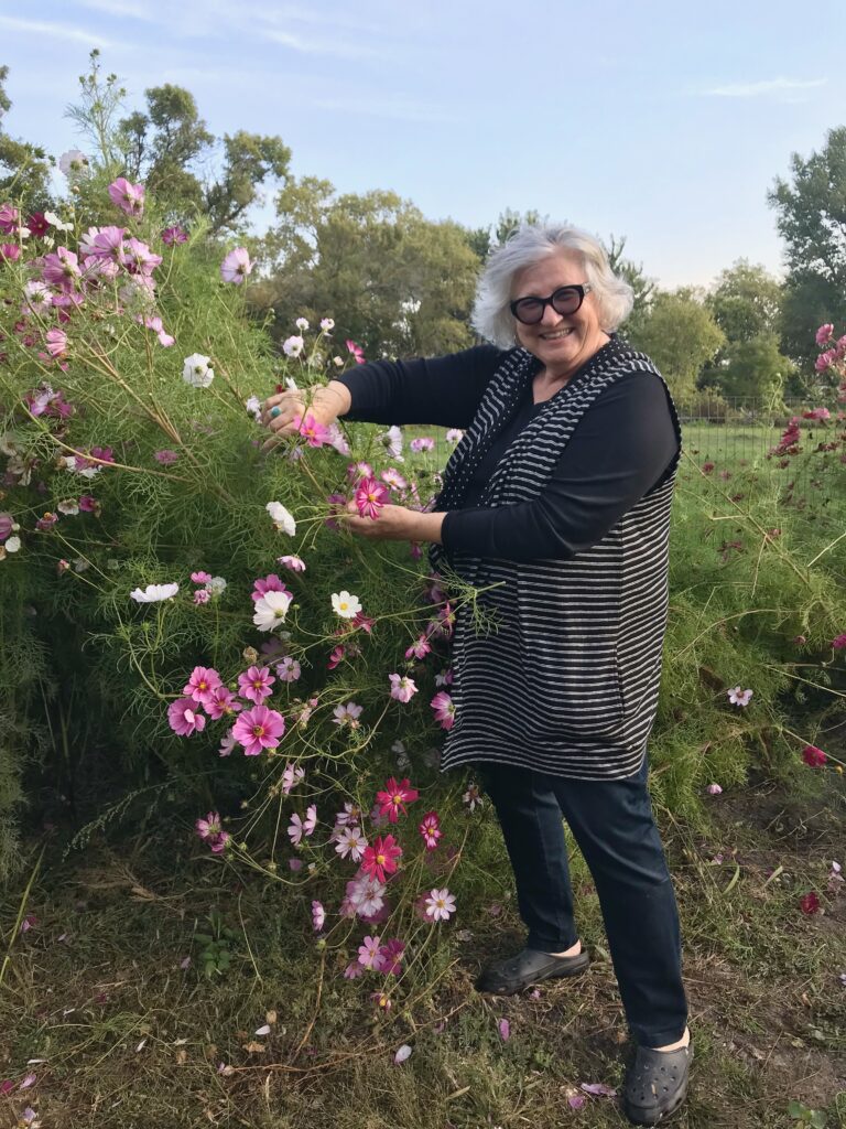 Marie standing by a large Cosmos flower plant