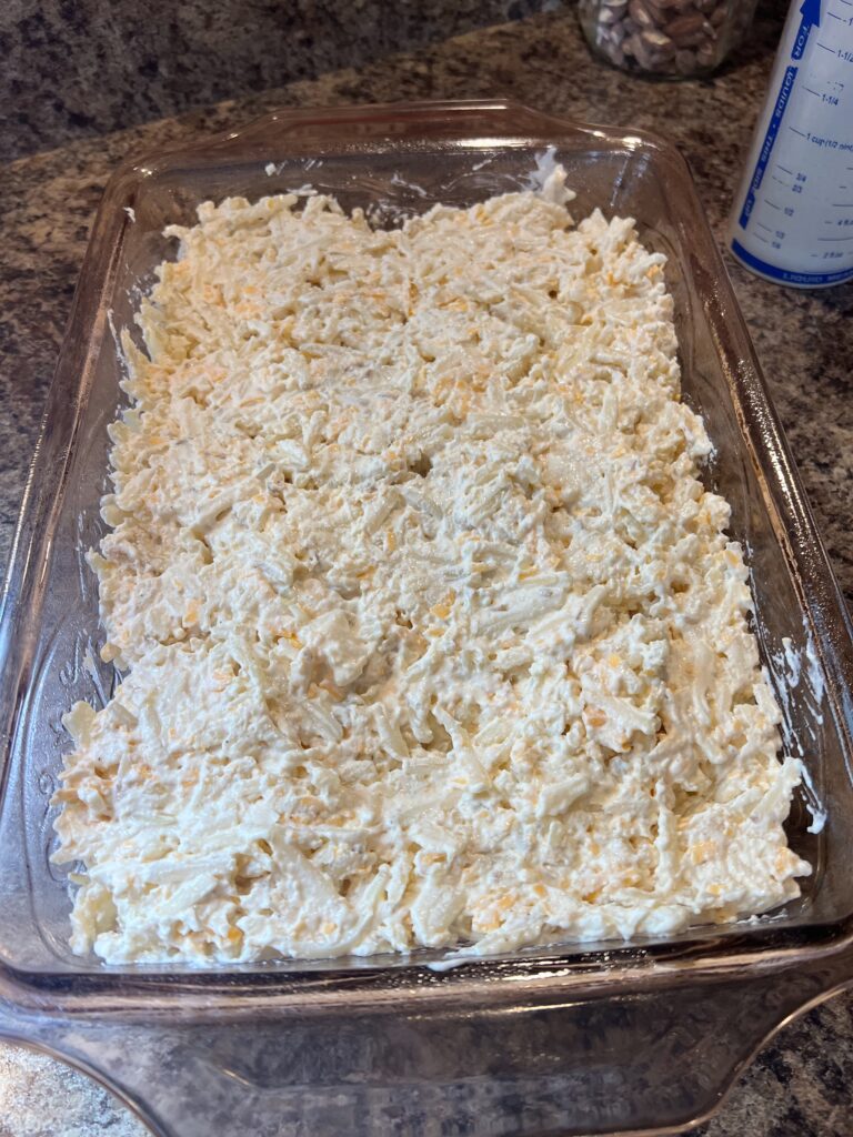 cheesy hash brown casserole spread in a 9x13 pan before baking 