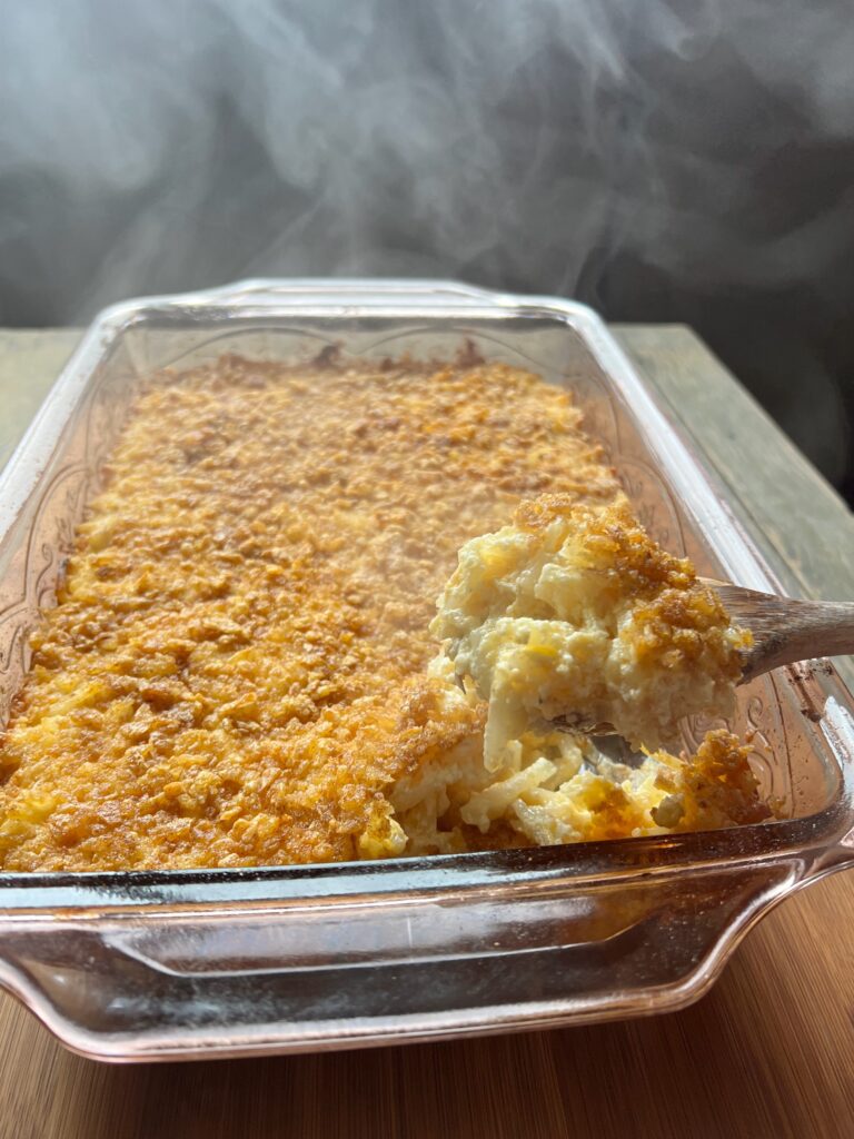 spoon with a scoop of funeral potatoes from a pan