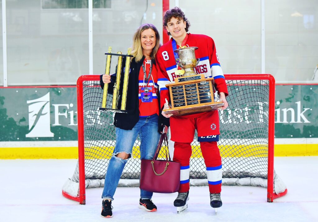 Leah and David on hockey rink with two trophies