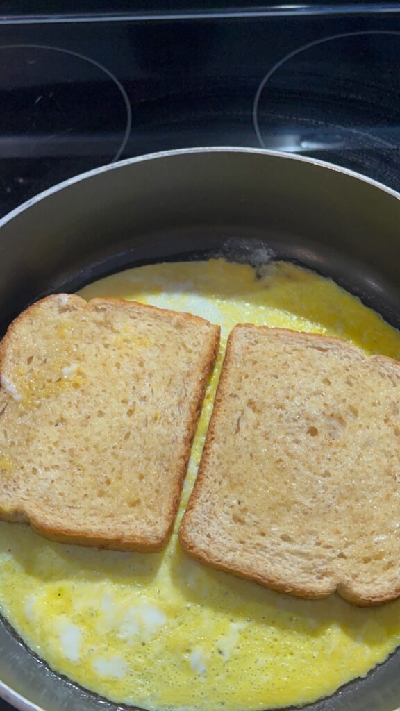 two slices of bread on top of scrambled eggs in a pan
