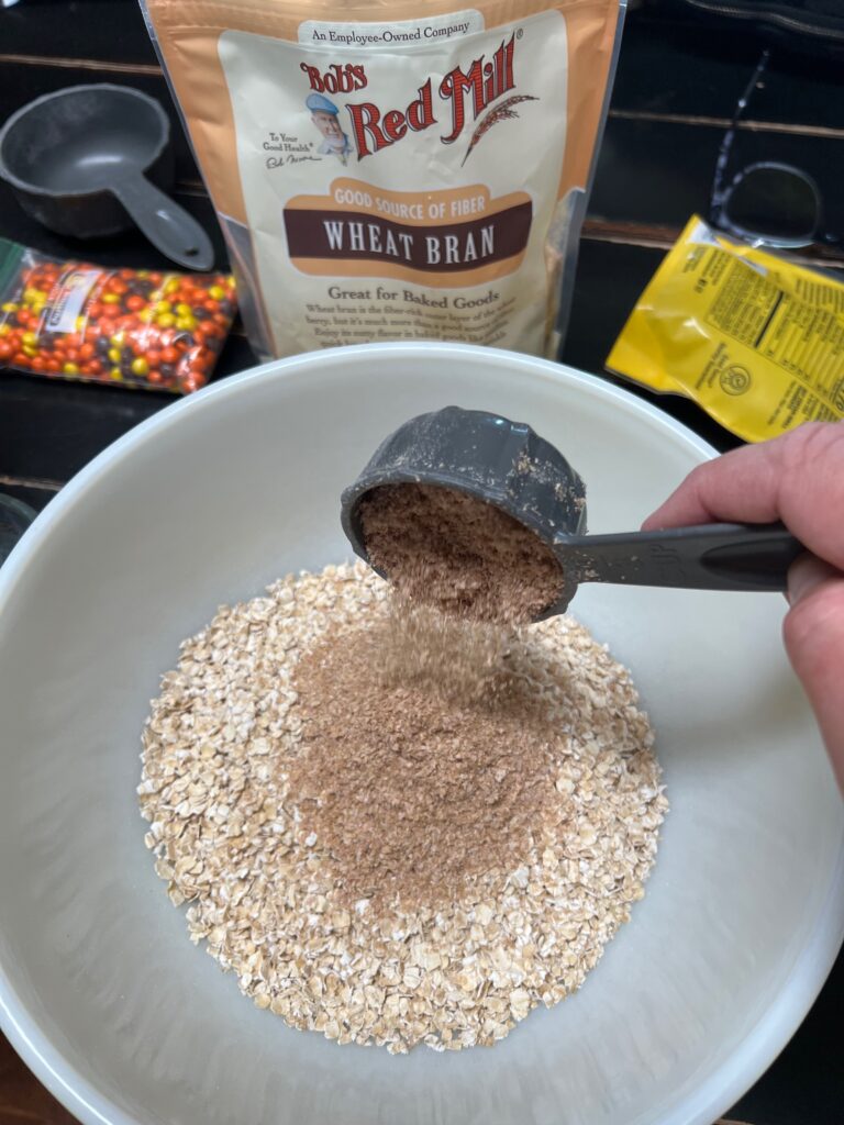 adding wheat bran to a bowl of oats
