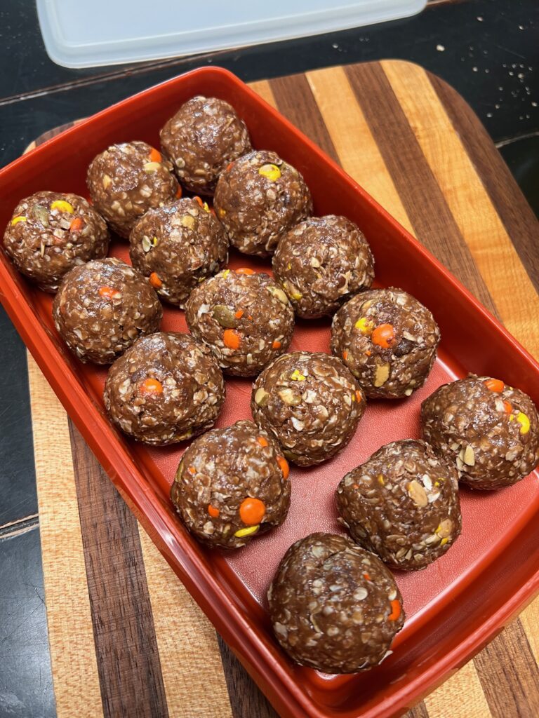 honey cocoa almond spread energy balls in an orange Tupperware container
