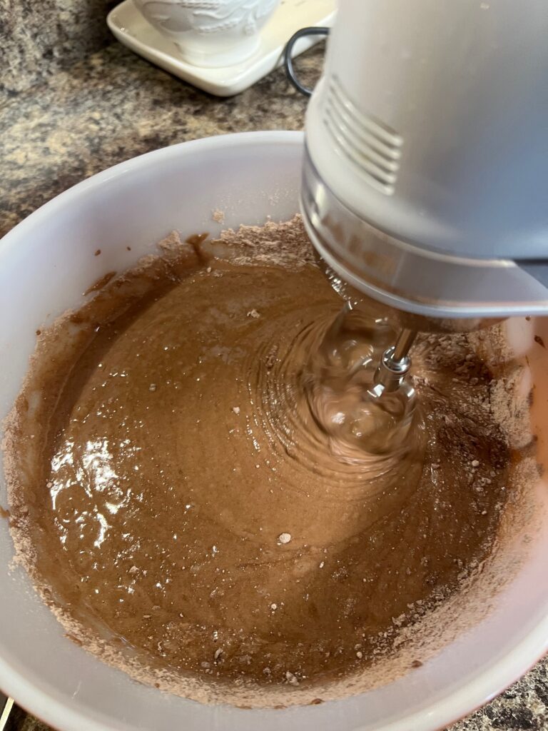 electric hand mixer beating turtle cake batter 