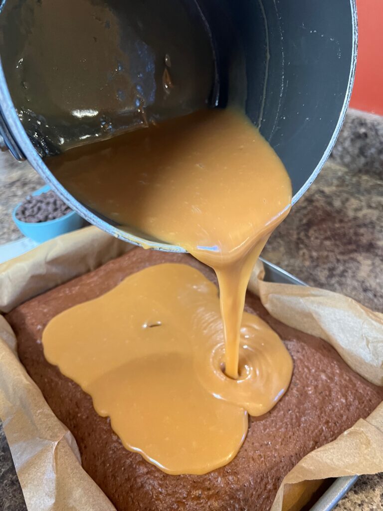 pouring the melted caramels, butter and evaporated milk over the baked cake
