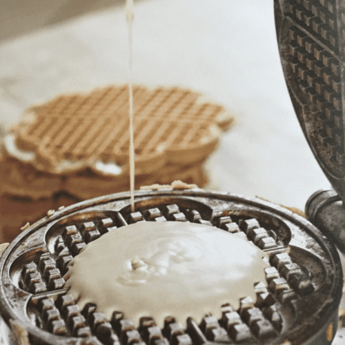 pouring waffle batter into a heart waffle iron