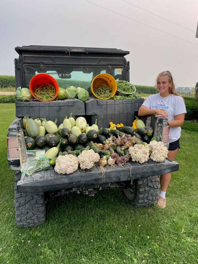 Lauren Schroeder standing by a Ranger loaded with fresh vegetables from her garden