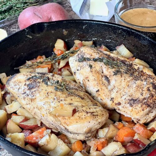 roast chicken and vegetables with jus in a cast iron skillet