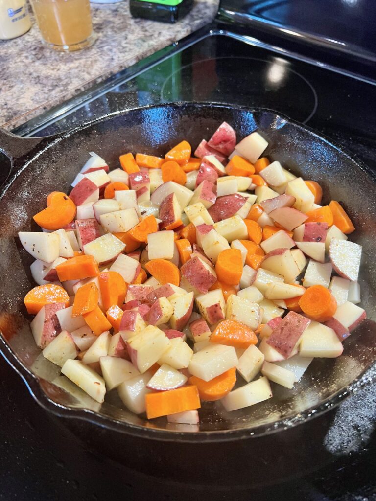 cast iron pan with diced potatoes and carrots 