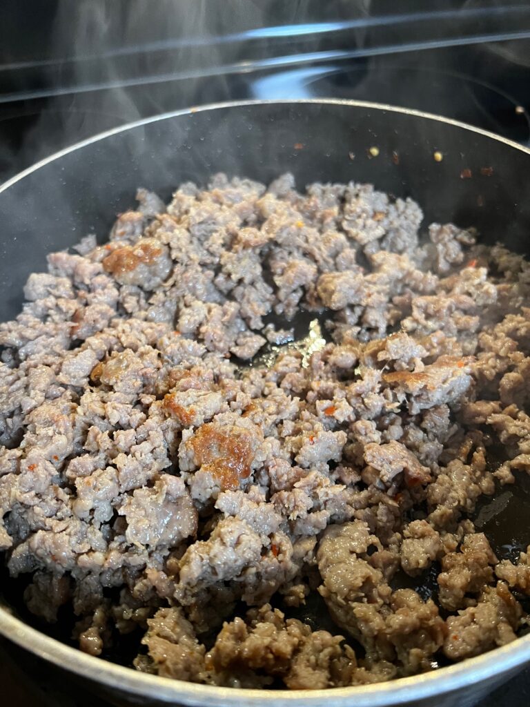 cooked pork sausage in a hot pan for sausage wontons