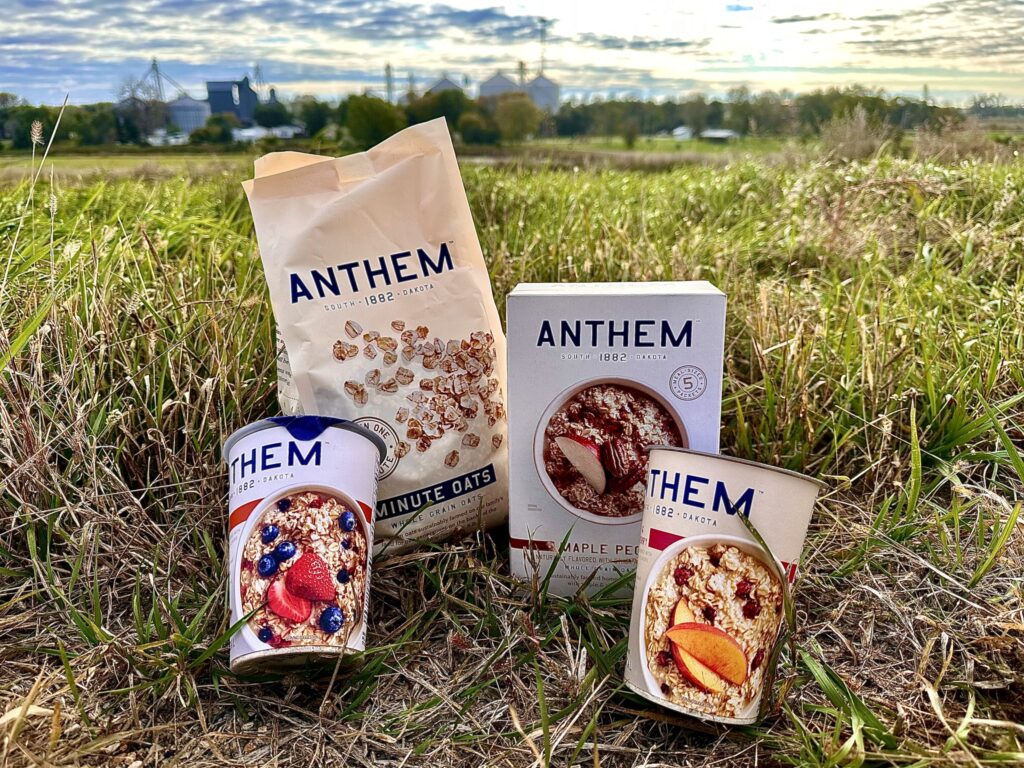 Anthem Oats products sitting on the ground in a farm field 