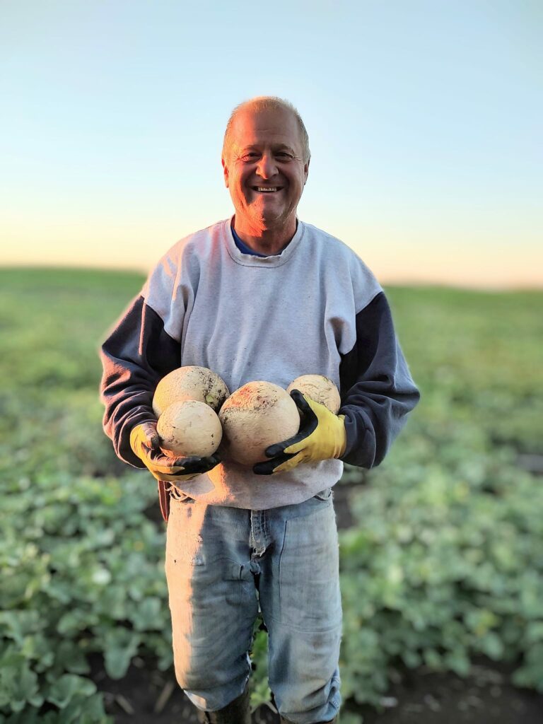 David Berndt in the field holding muskmelon 