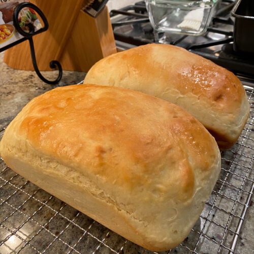 2 loaves of white everyday sandwich bread on a cooling rack