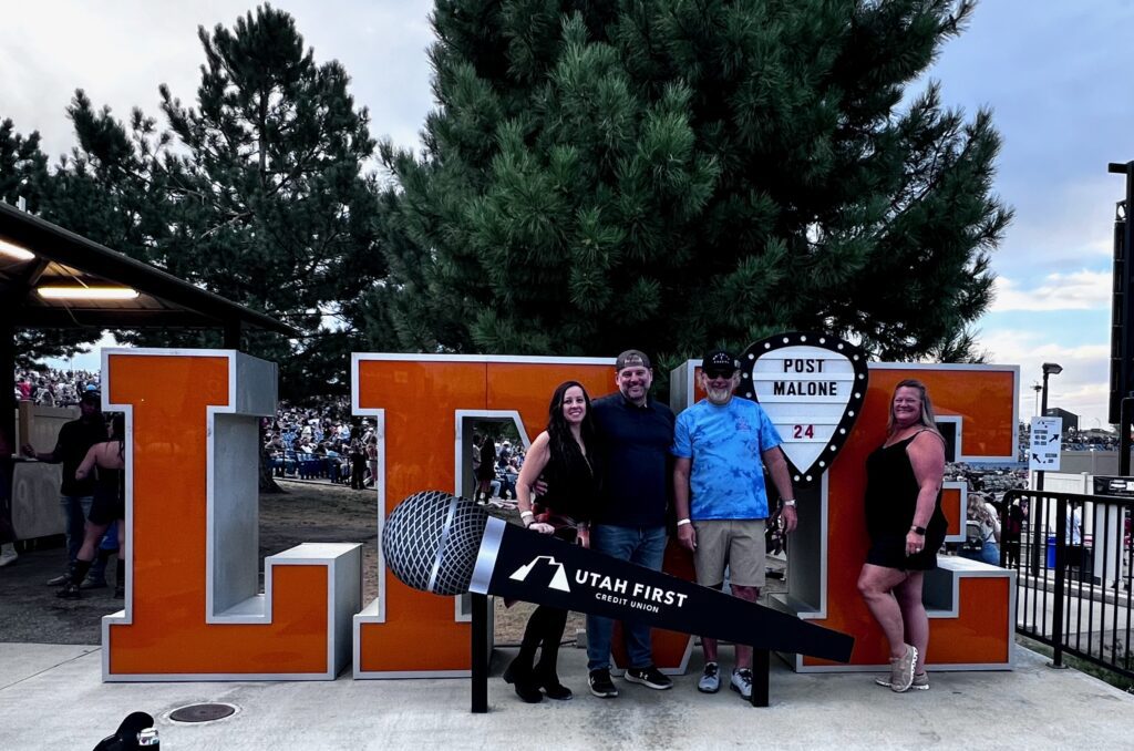 four people by an outdoor concert sign for Post Malone