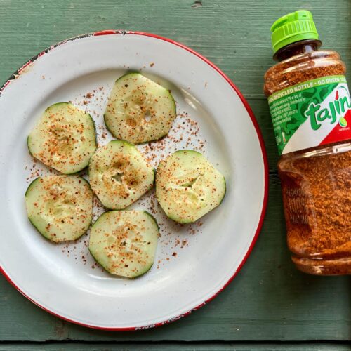 plate with tajin seasoned cucumbers and a bottle of tajin