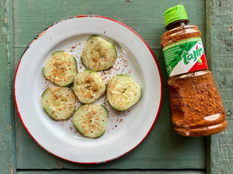 plate with tajin seasoned cucumbers and a bottle of tajin