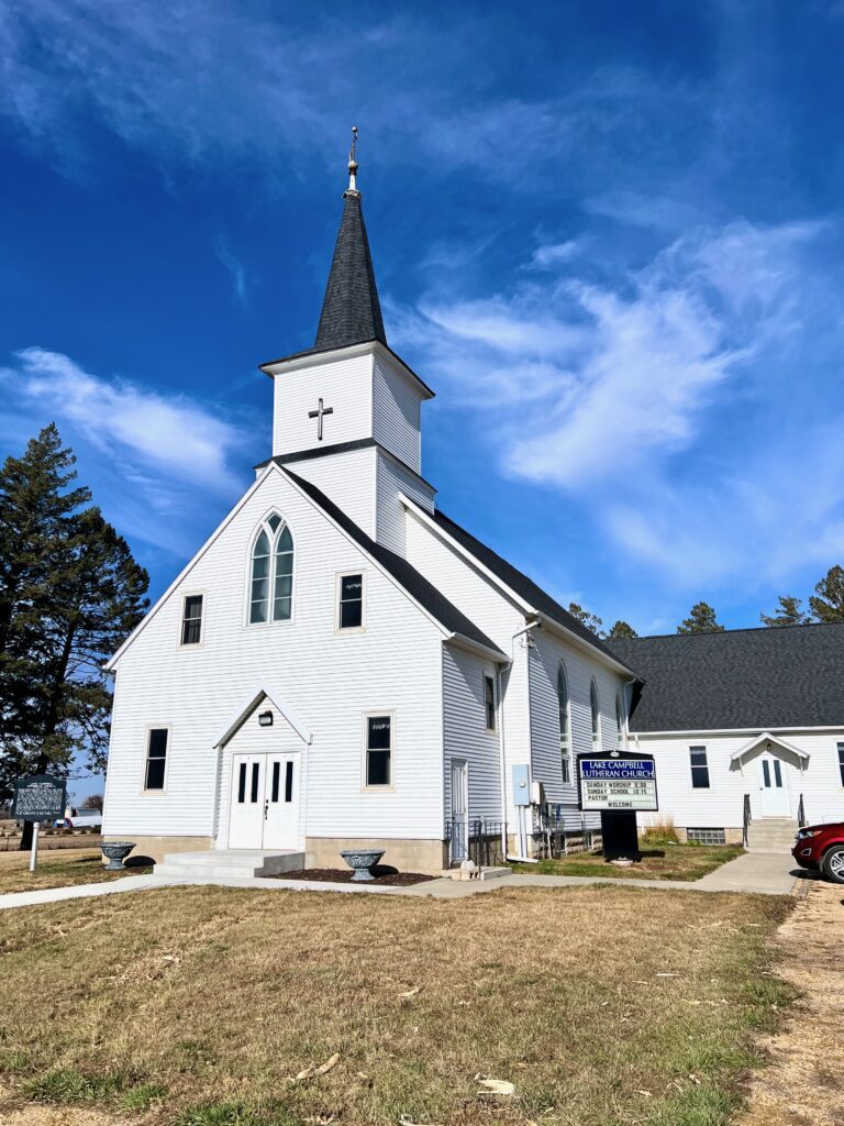 big white country church Lake Campbell Lutheran Church with a blue sky