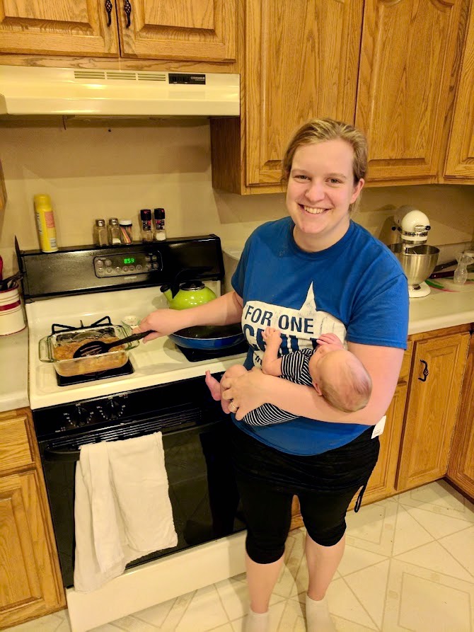 Amanda cooking in the kitchen and holding her baby 