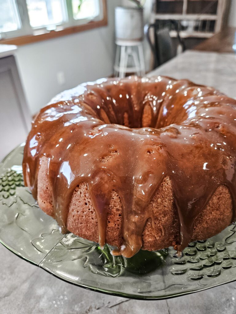 apple cider doughnut cake with caramel sauce on a green cake pedestal